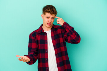 Young caucasian man isolated on blue background showing a disappointment gesture with forefinger.