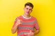 © Asier - Young caucasian man isolated on yellow background touches tummy, smiles gently, eating and satisfaction concept.