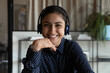 © fizkes - Screen view portrait of smiling young Indian female employee in earphones have webcam digital virtual event in office. Headshot of happy ethnic woman worker in headphones talk speak on video call.
