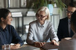 © fizkes - Smiling multiethnic businesspeople gather at desk in office talk discuss business ideas together. Happy diverse multiracial employees colleagues brainstorm cooperate at meeting. Teamwork concept.
