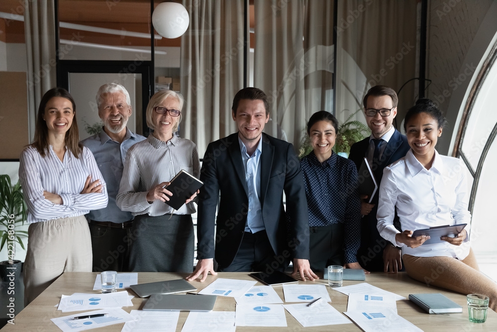 Portrait of happy multiracial businesspeople stand pose at workplace in modern office. Smiling diverse multiethnic employees colleagues show leadership unity. Success, employment concept. - obrazy, fototapety, plakaty 