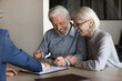 © fizkes - Excited mature Caucasian couple clients sign paper contract with real estate agent or broker buy house together. Smiling older man and woman spouses put signature make health insurance agreement.