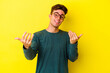 © Asier - Young caucasian man isolated on yellow background pointing with finger at you as if inviting come closer.