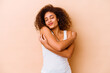 © Asier - Young african american woman isolated on beige background hugs, smiling carefree and happy.