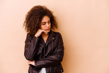 Wall Mural - Young african american woman isolated on beige background looking sideways with doubtful and skeptical expression.