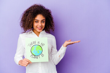 Wall Mural - Young African American woman holding a There is no planet B placard isolated showing a copy space on a palm and holding another hand on waist.