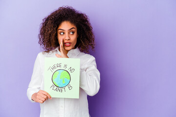 Wall Mural - Young African American woman holding a There is no planet B placard isolated is saying a secret hot braking news and looking aside