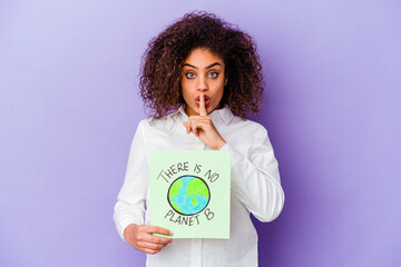 Wall Mural - Young African American woman holding a There is no planet B placard isolated keeping a secret or asking for silence.