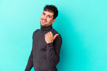 Wall Mural - Young caucasian man isolated on blue background points with thumb finger away, laughing and carefree.