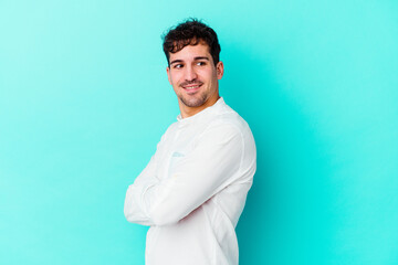 Wall Mural - Young caucasian man isolated on blue background laughing and having fun.