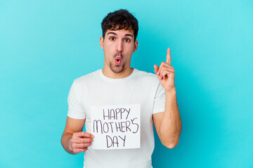 Wall Mural - Young caucasian man holding a happy mothers day placard isolated having some great idea, concept of creativity.