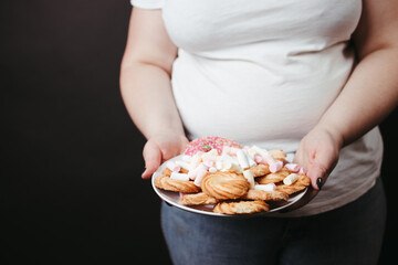 Wall Mural - Overweight woman holding plate with tasty sweets