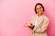 © Asier - Young business mixed race woman isolated on pink background holding a copy space on a palm.