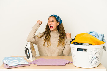 Wall Mural - Young caucasian woman ironing clothes isolated raising fist after a victory, winner concept.