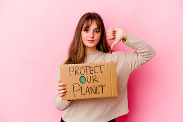 Wall Mural - Young caucasian woman holding a Protect our planet placard isolated showing a dislike gesture, thumbs down. Disagreement concept.