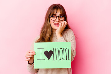Wall Mural - Young caucasian woman holding a I love mom isolated biting fingernails, nervous and very anxious.