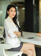 © bongkarn - Side view of businesswoman arms crossed sitting and smiling to camera