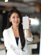 © bongkarn - Portrait of businesswoman showing smartphone with mock up screen to camera
