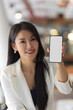 © bongkarn - Cropped shot of businesswoman showing smartphone with mock up screen to camera