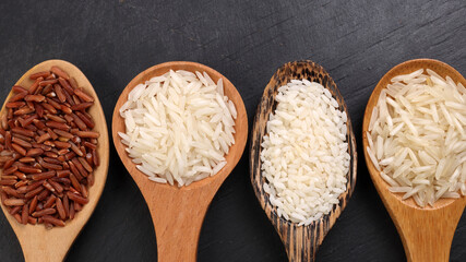 Long grain basmati medium grain jasmine short grain pilaf polau risotto brown low glycaemic index gi rice in wooden spoon on black background copy text space top flat lay view