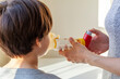 © Grandbrothers - A caucasian woman is giving emergency asthma medication to a small kit during an attack. She uses aerosol chamber with valve mask to deliver bronchodilators or corticosteroids to relieve symptoms.
