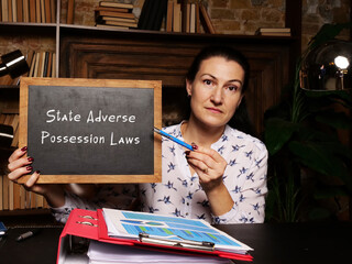 Wall Mural - High resolution business Woman holding chalkboard with written text State Adverse Possession Laws - closeup shot.