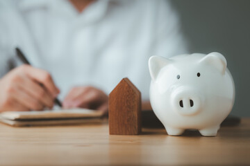 Poster - piggy bank with man doing finances and calculate on desk about cost at home office..concept of save, investment, Financial planning.