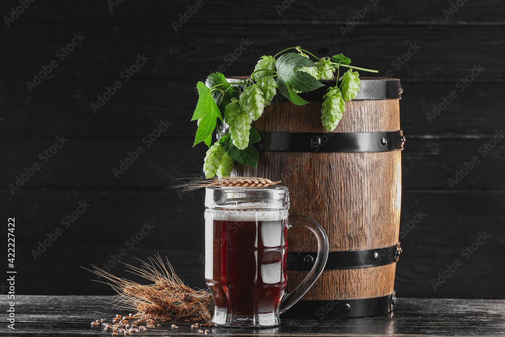Composition with mug of fresh beer on dark wooden background