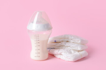 Bottle of milk for baby and diapers on color background