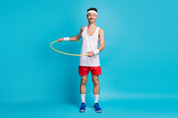 Wall Mural - Photo of young excited man happy smile spin plastic circle around waist isolated over blue color background