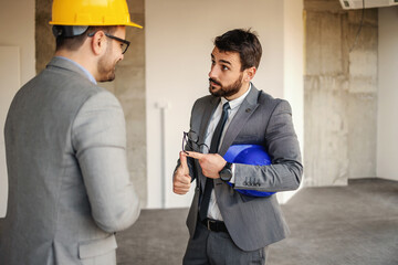 Wall Mural - Businessman standing with architect and discussing about building big shopping center.