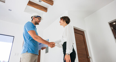 Home renovation concept - builder with blueprint shaking partner hand