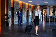 © Dusan Petkovic - Full length of middle-aged blonde in formal wear walking in the lobby of a fancy hotel and pulling her suitcase. She escaped from daily problems.