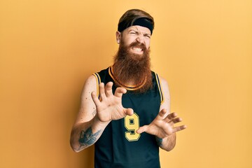 Canvas Print - Redhead man with long beard wearing basketball uniform disgusted expression, displeased and fearful doing disgust face because aversion reaction. with hands raised