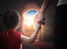 Child's Hand Holding Mother's Finger On Blurred The Cross Of Jesus Christ Background.