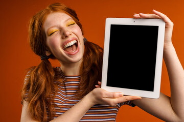 Wall Mural - Ginger laughing woman with tails showing tablet pc