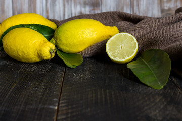 Lemons and leaves on black wooden background