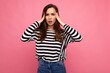 © Ivan Traimak - Photo of young sad upset tired attractive brunet woman with sincere emotions wearing casual striped pullover isolated on pink background with copy space and having headache