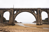 Fototapeta Niebo - stone bridge over a river on the beach