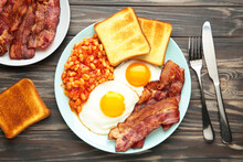 Traditional Full English Breakfast - Fried Eggs, Beans, Bacon And Toast On Brown Background.