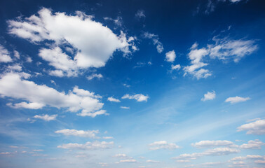 Blue sky background with white fluffy clouds in the fresh sunny day.