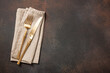 Table place setting with golden cutlery on rusted metallic surface