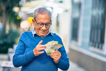 Wall Mural - senior grey-haired man smiling happy counting russian ruble banknotes at the city.