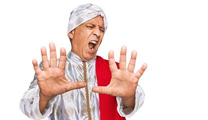 Poster - Senior hispanic man wearing tradition sherwani saree clothes afraid and terrified with fear expression stop gesture with hands, shouting in shock. panic concept.