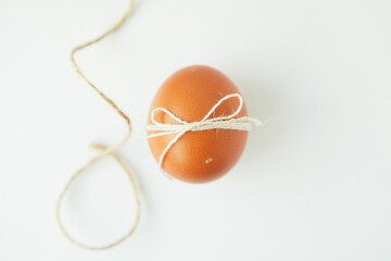 Brown egg wrapped with thread on white background
