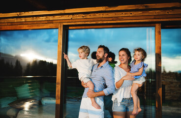 Wall Mural - family with small children standing by wooden cabin, holiday in nature concept.