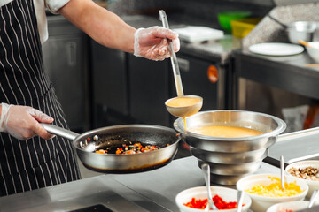 Wall Mural - Restaurant cooks preparing food in the kitchen with vegetables