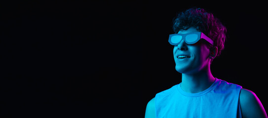 Portrait of young man isolated on dark multicolored background in neon light