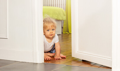 Toddler boy sit looking from the room door