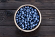 Blueberries in a wooden bowl on a dark wooden background. Fresh harvest of huckleberry berries from the garden. on a wooden table.